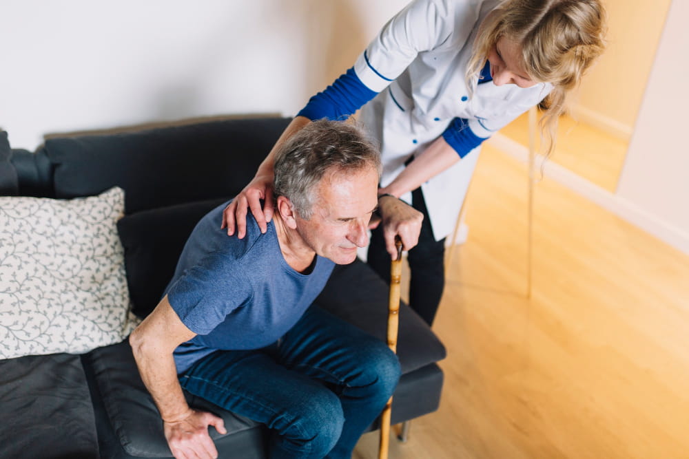 Nella foto, un anziano con problemi di motilità che viene aiutato da un caregiver.